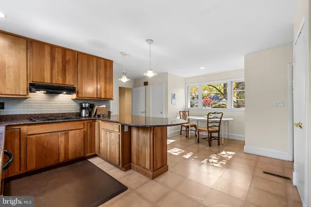 a open kitchen with stainless steel appliances granite countertop a stove top oven a sink a dining table and chairs with wooden floor