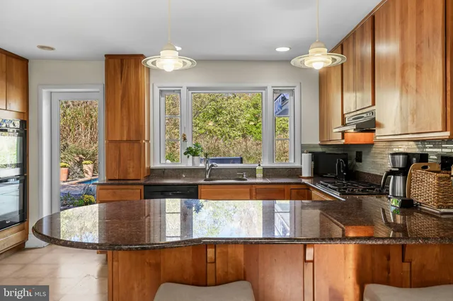 a kitchen with kitchen island granite countertop a large window cabinets and stainless steel appliances