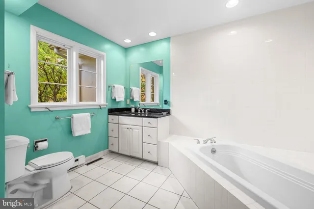 a bathroom with a granite countertop toilet sink and mirror