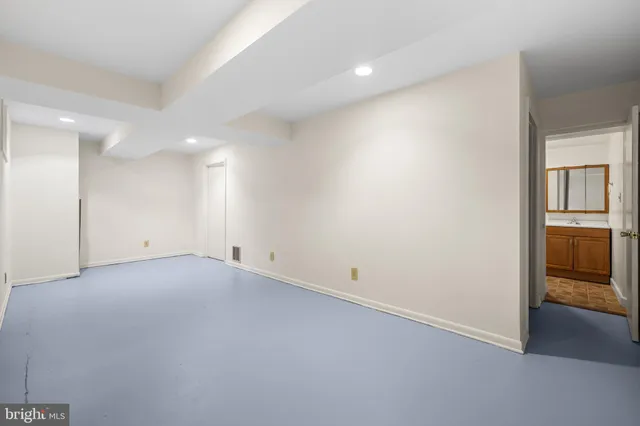 an empty room with kitchen view and windows