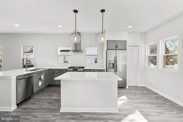 a large kitchen with stainless steel appliances kitchen island a large counter top and a wooden floors