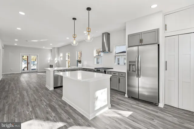 a kitchen with stainless steel appliances kitchen island granite countertop a refrigerator and a sink