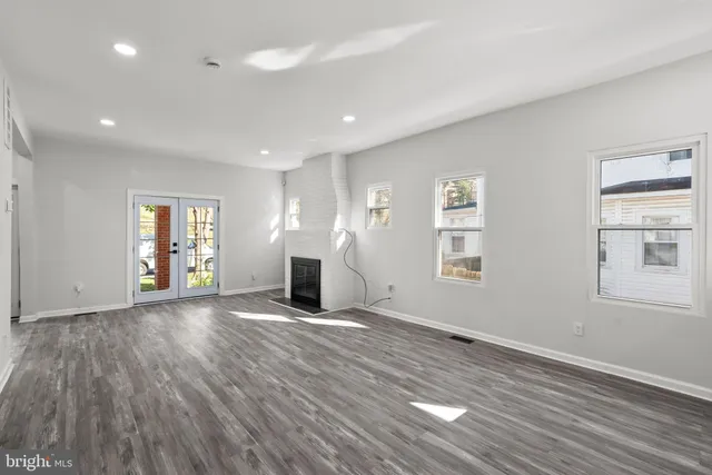 a view of an empty room with wooden floor and window