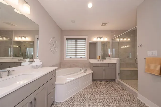 a bathroom with a bathtub a double vanity sink and mirror