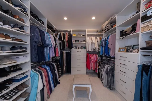 a view of walk in closet with clothes and shoes