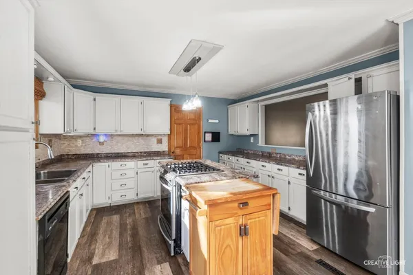 a kitchen with stainless steel appliances granite countertop a refrigerator stove microwave and sink