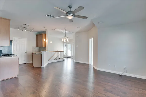 an empty room with wooden floor and a kitchen