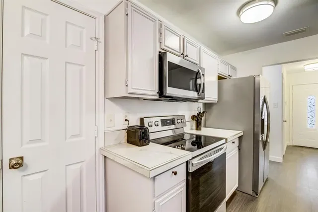 a kitchen with stainless steel appliances granite countertop white cabinets a refrigerator and a stove