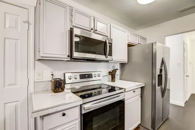 a kitchen with stainless steel appliances white cabinets white stove a microwave and a refrigerator