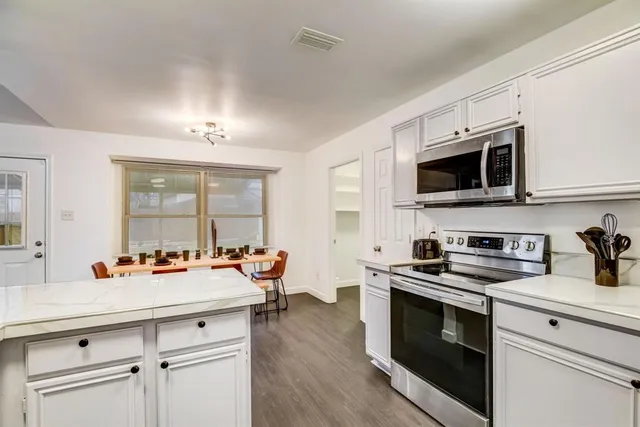 a kitchen with stainless steel appliances a stove a sink and white cabinets