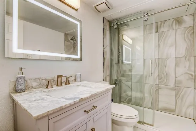 a bathroom with a granite countertop sink a toilet and shower