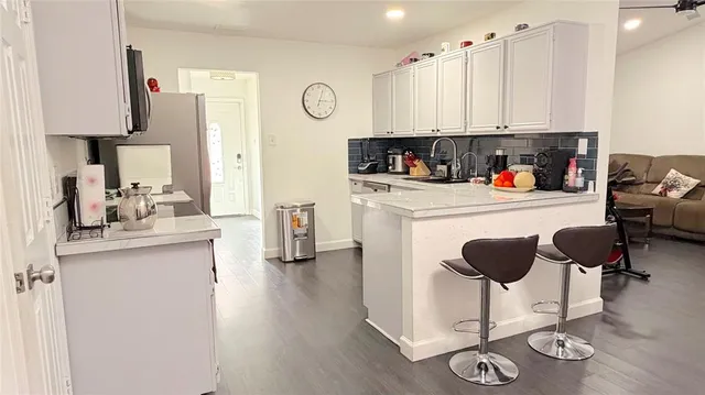 a kitchen with stainless steel appliances granite countertop a stove top oven a refrigerator a sink and dishwasher with wooden floor