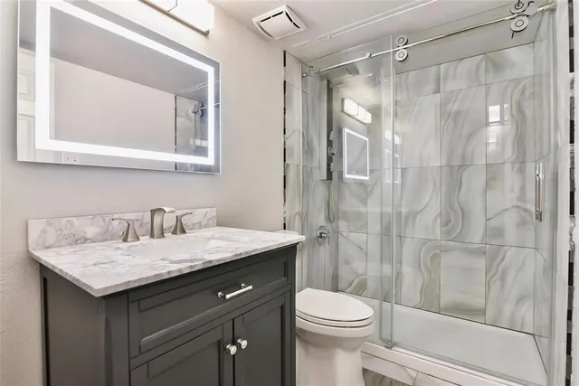 a bathroom with a granite countertop sink toilet and shower