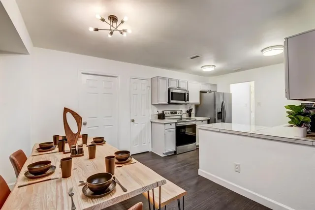 a kitchen with a refrigerator a stove cabinets and a dining table