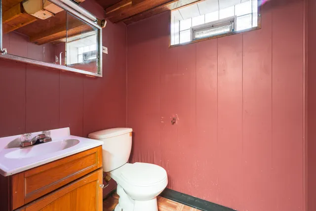 a toilet sitting in a bathroom next to a wooden cabinet