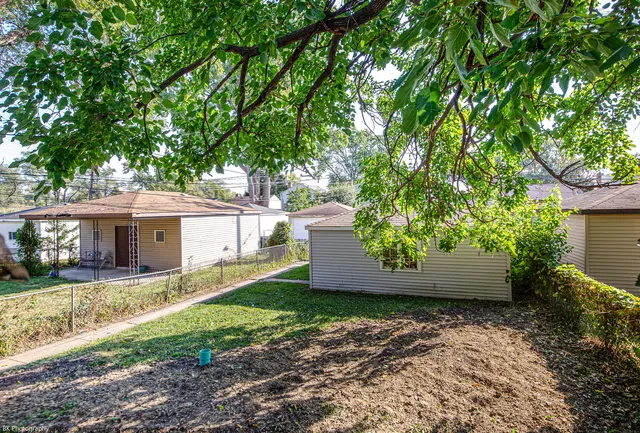 a view of a house with a yard and large tree