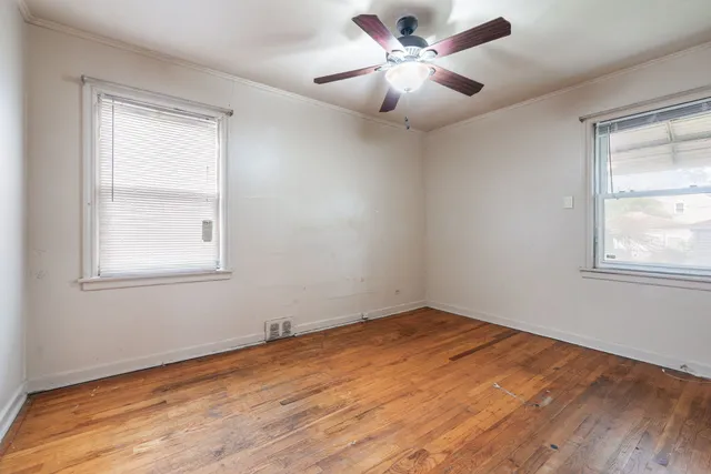 a view of empty room with wooden floor and fan