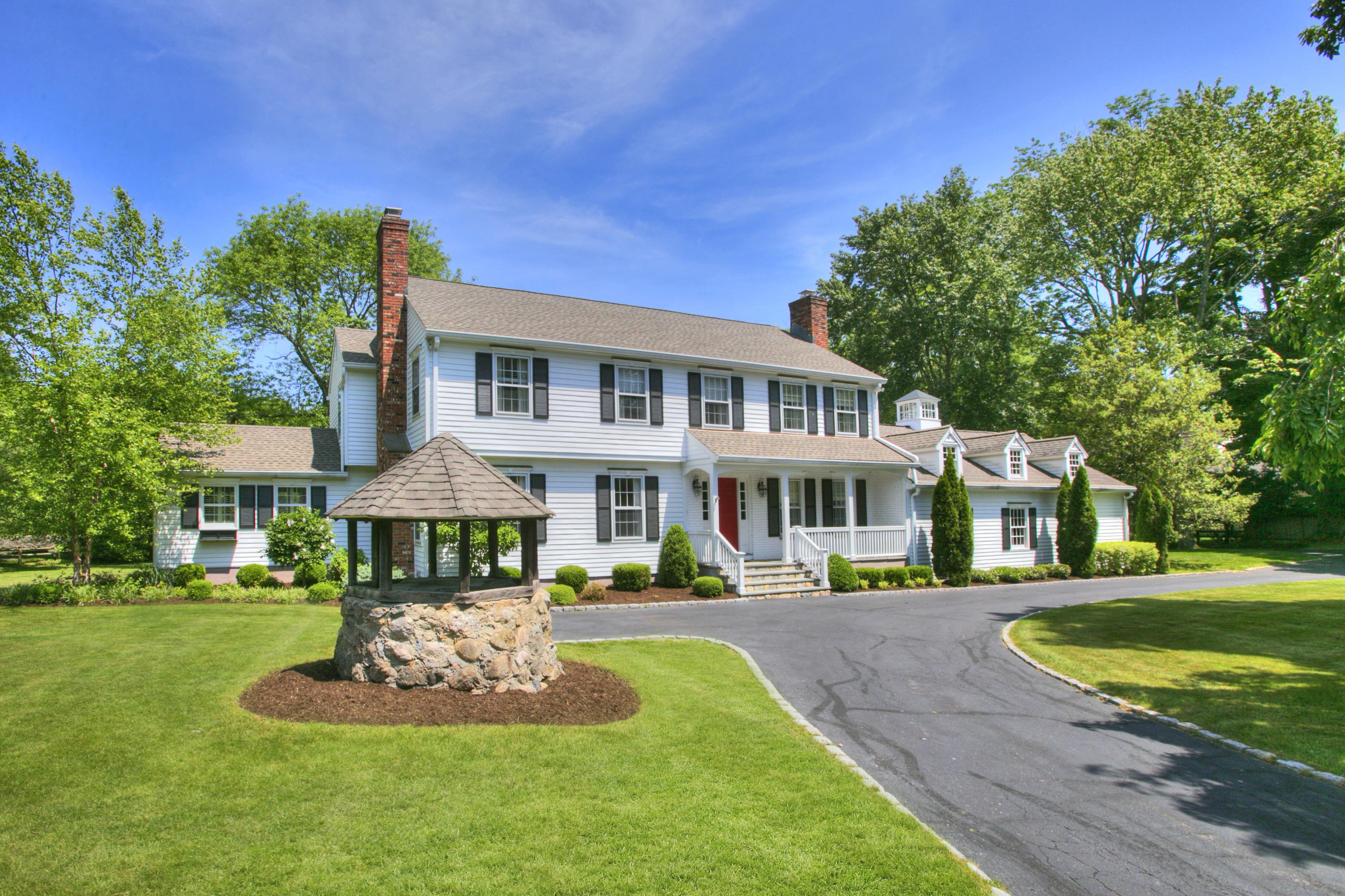 195 Ponus Ridge Road New Canaan, CT 06840 - Photo 2 of 28 a front view of a house with a yard table and chairs