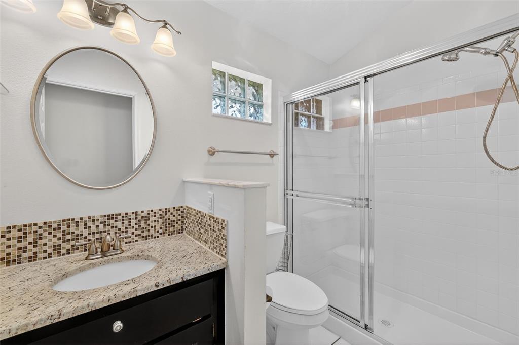 5500 Laver Street Leesburg, FL 34748 - Photo 19 of 35 a bathroom with a granite countertop sink toilet a mirror and a shower
