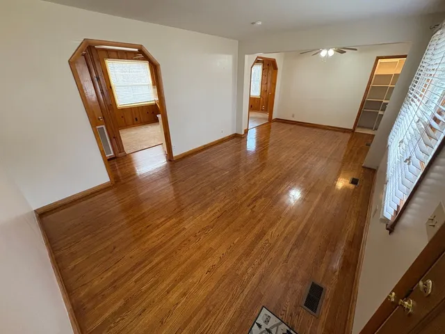 a view of an empty room with wooden floor and a window