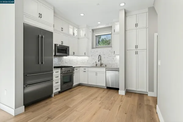 a kitchen with white cabinets and stainless steel appliances