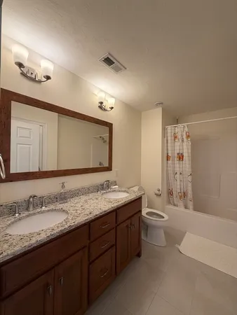 a bathroom with a granite countertop sink mirror and toilet