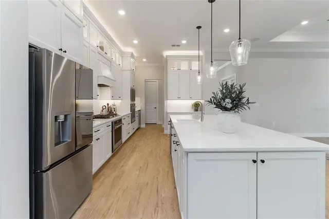 a large kitchen with kitchen island a large island a sink a stove and a wooden floors