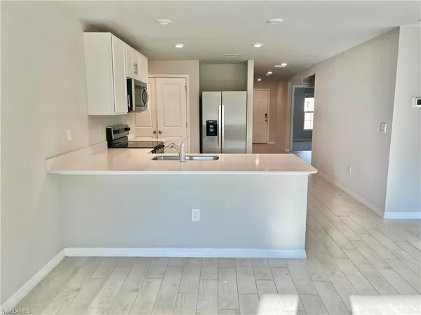 a large kitchen with kitchen island a sink a stove a refrigerator and white cabinets