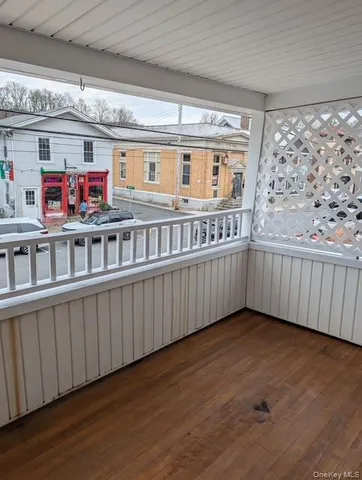 a view of an empty room with wooden floor and windows