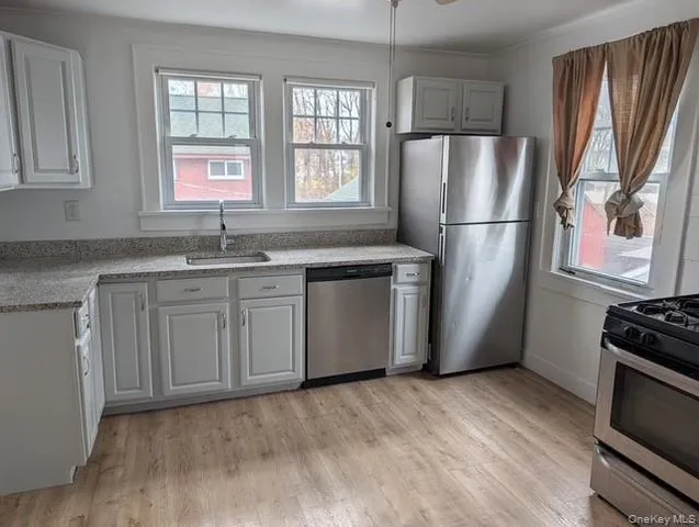 a kitchen with stainless steel appliances granite countertop a refrigerator sink and wooden floor