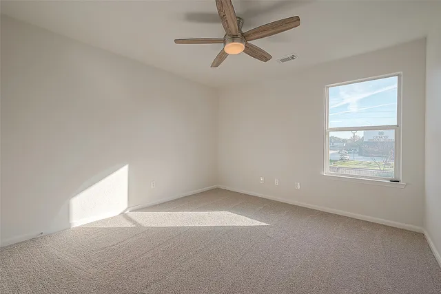an empty room with a ceiling fan and a window
