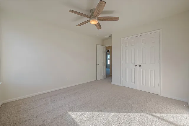 an empty room with a ceiling fan and window