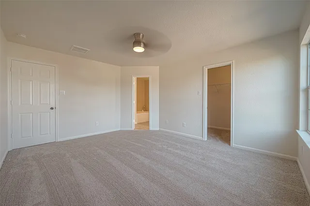 a view of an empty room and chandelier fan