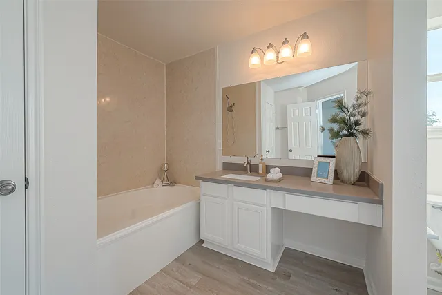 a bathroom with a granite countertop sink and a mirror a bathtub