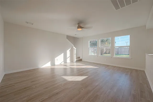 an empty room with wooden floor and windows