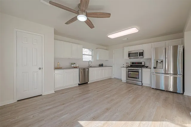 a kitchen with a refrigerator cabinets and wooden floor