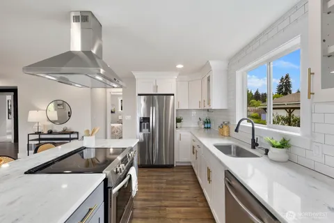 a kitchen with stainless steel appliances granite countertop a sink a stove and a refrigerator