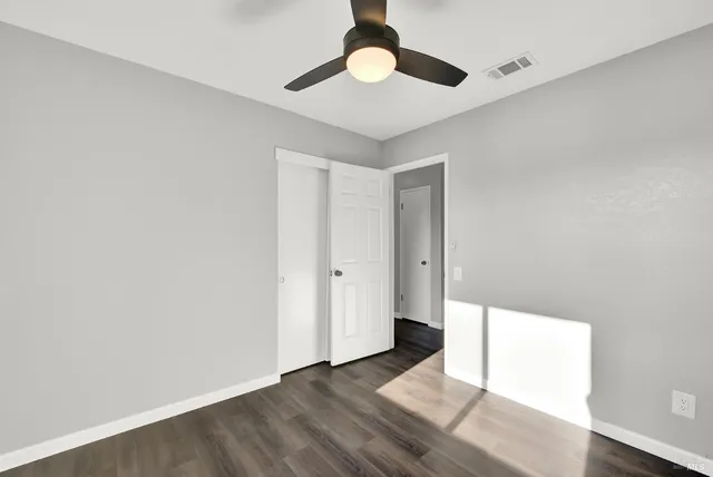 an empty room with wooden floor chandelier fan and closet area