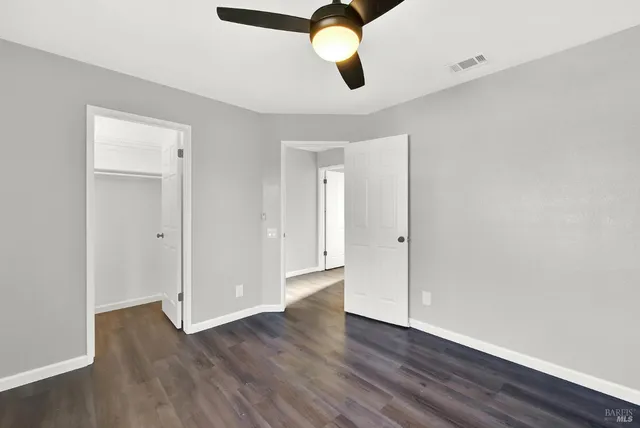 an empty room with wooden floor ceiling fan and window