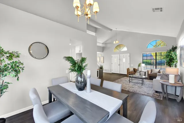 a living room with couches a table and chairs with wooden floor