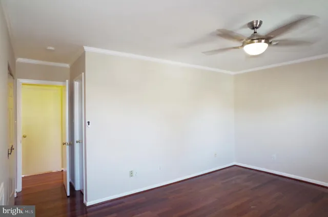 an empty room with wooden floor and fan