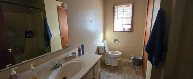 a bathroom with a granite countertop toilet a sink and a mirror