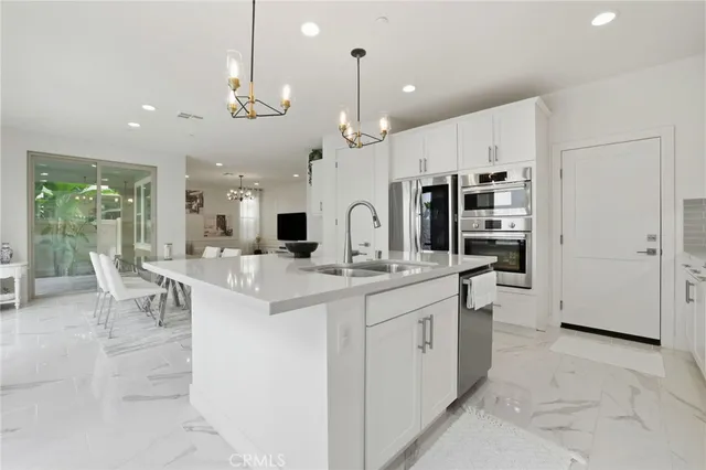 a large kitchen with kitchen island a chandelier and refrigerator