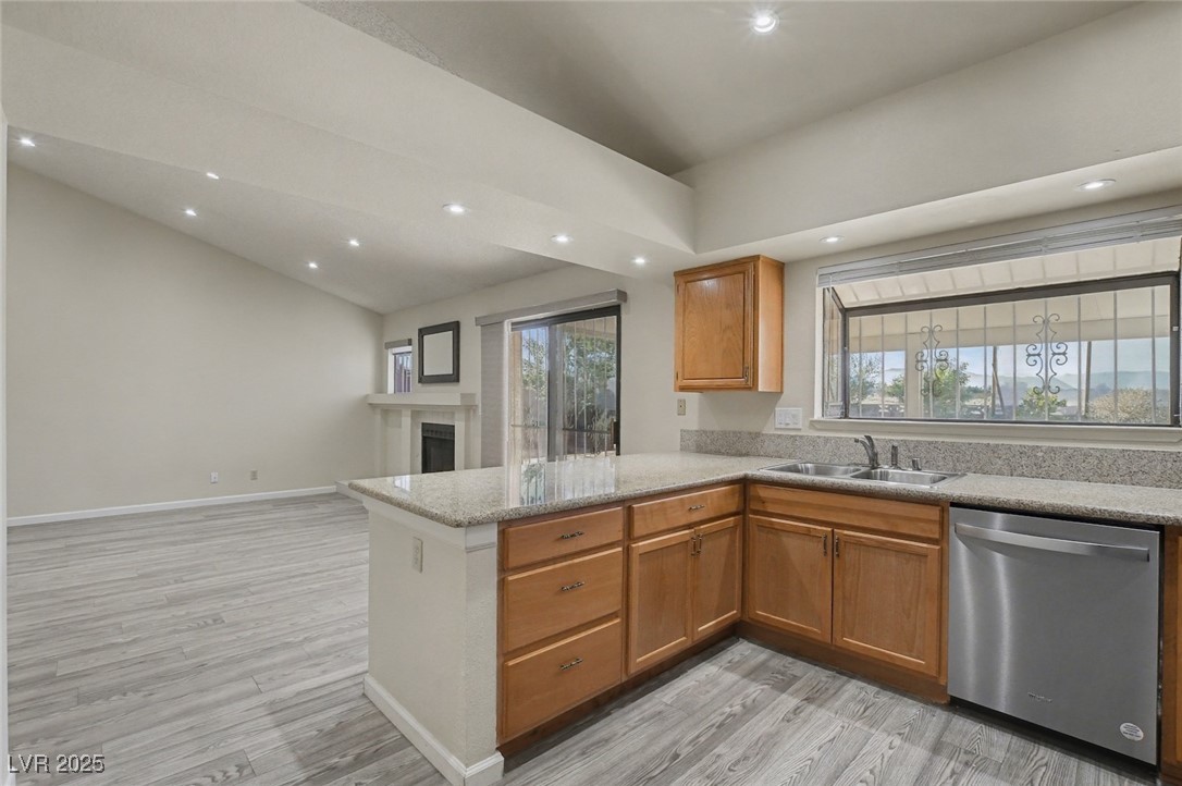 7951 Aspendale Drive Las Vegas, NV 89123 - Photo 42 of 42 Kitchen with brown cabinetry, stainless steel dishwasher, light wood-type flooring, open floor plan, and vaulted ceiling