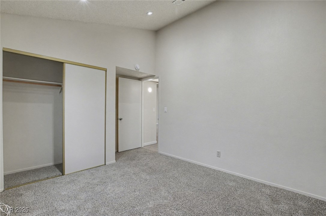 7951 Aspendale Drive Las Vegas, NV 89123 - Photo 28 of 42 Unfurnished bedroom with light colored carpet, a textured ceiling, a closet, high vaulted ceiling, and recessed lighting