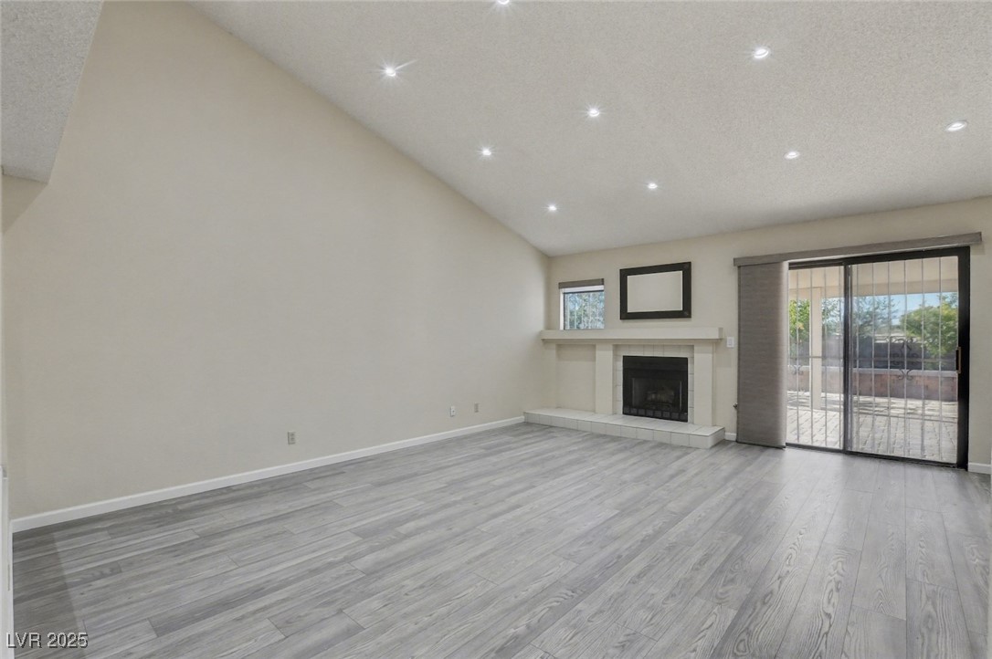 7951 Aspendale Drive Las Vegas, NV 89123 - Photo 6 of 42 Unfurnished living room featuring light wood-style floors, a fireplace, high vaulted ceiling, a textured ceiling, and recessed lighting