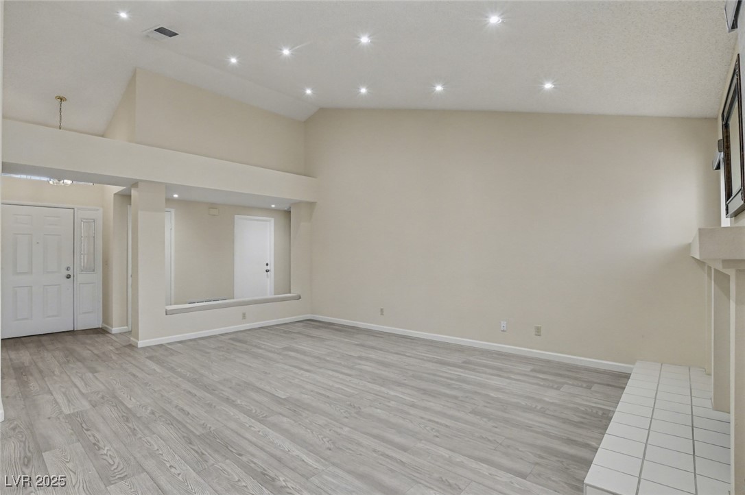 7951 Aspendale Drive Las Vegas, NV 89123 - Photo 9 of 42 Unfurnished living room featuring light wood finished floors, recessed lighting, a fireplace, and high vaulted ceiling