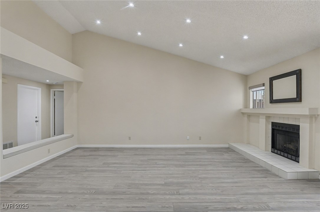 7951 Aspendale Drive Las Vegas, NV 89123 - Photo 10 of 42 Unfurnished living room featuring light wood finished floors, recessed lighting, a fireplace, and high vaulted ceiling