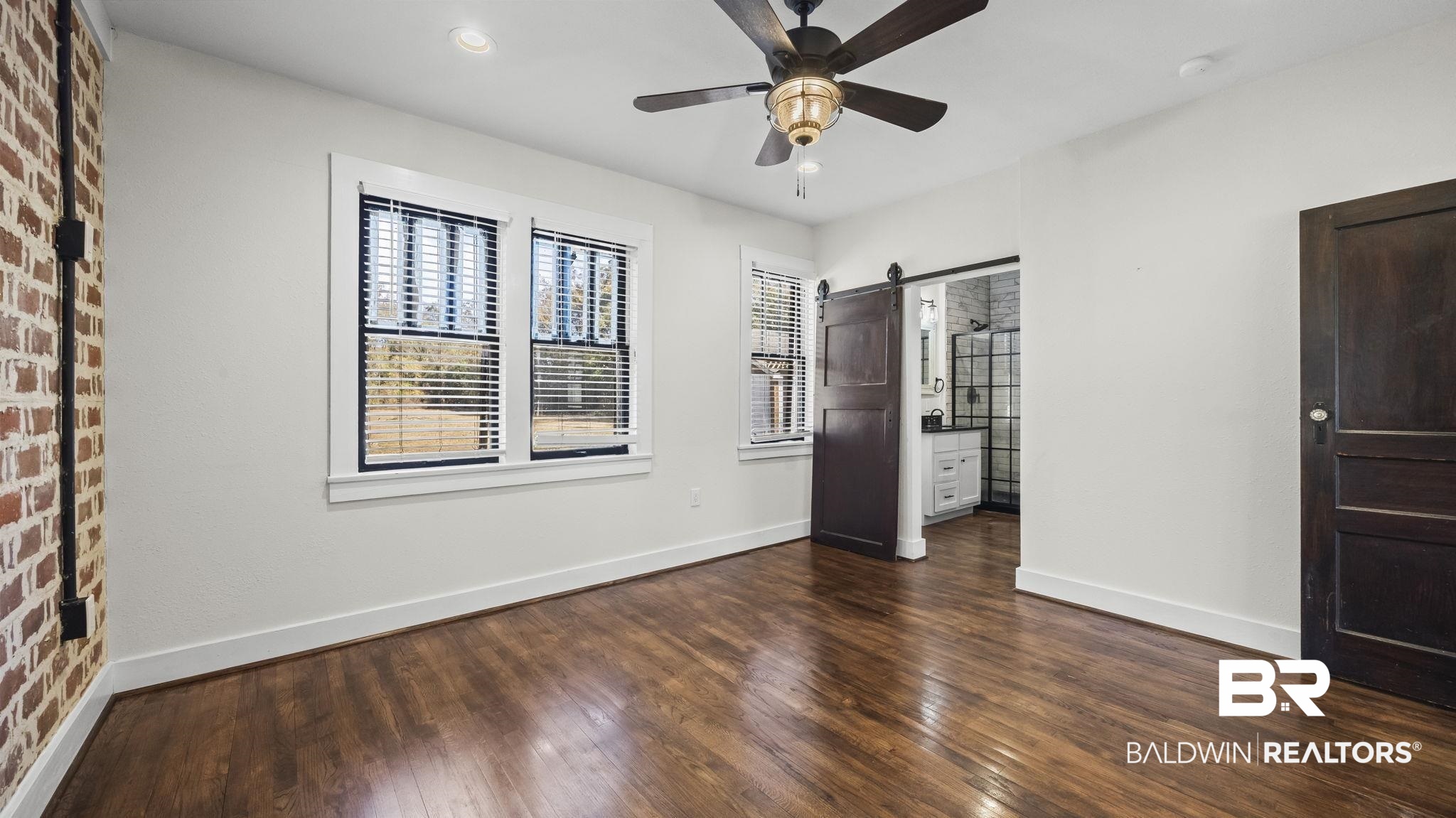 24701 Highway 98 Elberta, AL 36530 - Photo 15 of 32 Unfurnished bedroom featuring a barn door, dark wood-style flooring, ceiling fan, and connected bathroom