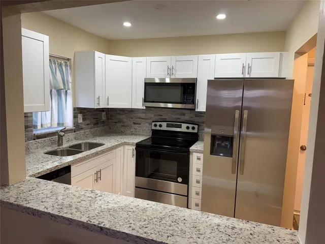 a kitchen with granite countertop a refrigerator and a stove top oven
